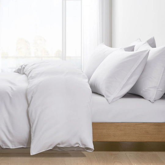 White anti-allergy duvet and pillows made up on a wooden bed frame in a bright, sunlit bedroom