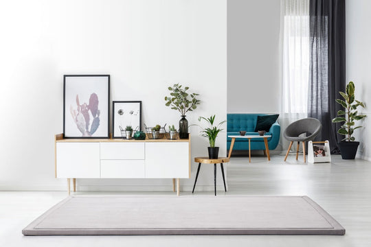 Gray yoga mat on light wood floor in modern minimalist living room with teal furniture and plants