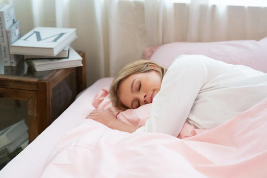 Woman sleeping on her side under a pink anti-allergy duvet beside a wooden bedside table