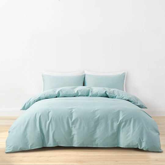 Pale aqua Momomi anti-allergy duvet cover and pillow shams on a wooden bed against a plain wall
