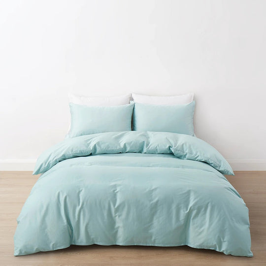 Pale aqua duvet cover and matching pillows on a made bed against a plain wall